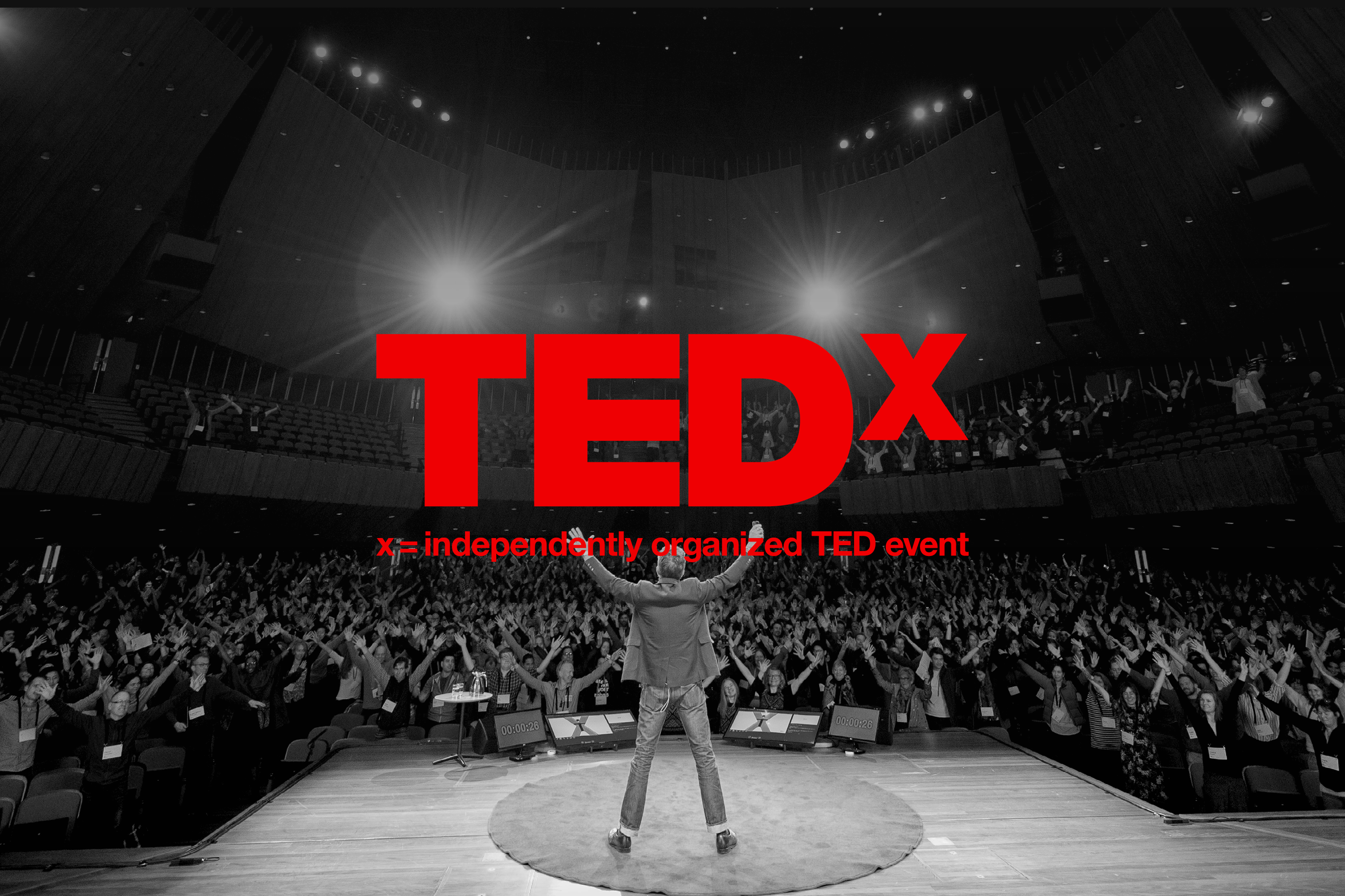 Tedx Christchurch - Strategy Creative - Speaker on the stage with his arms up in the air with the crowd following the speakers lead while they're all standing